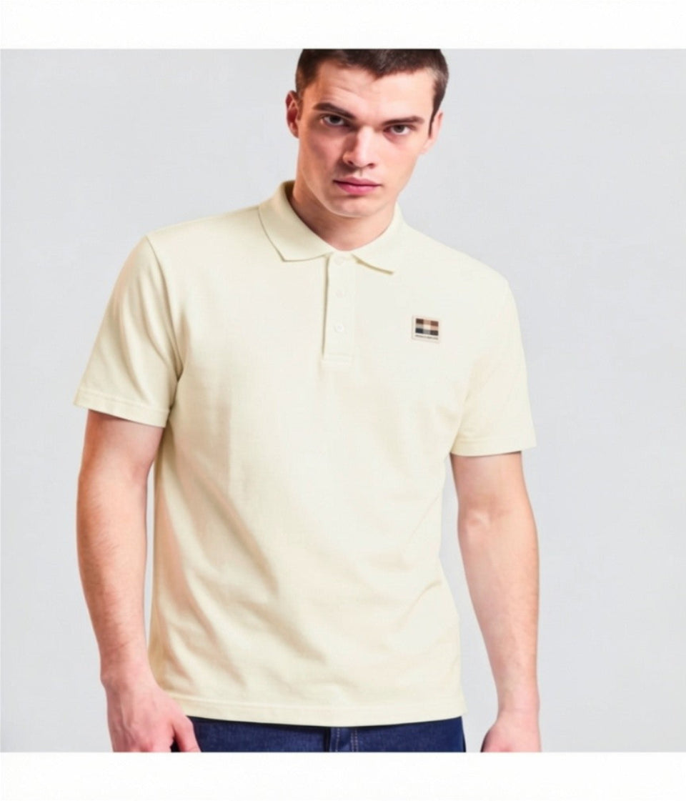 Man wearing a light-colored polo shirt with a small logo on a plain background