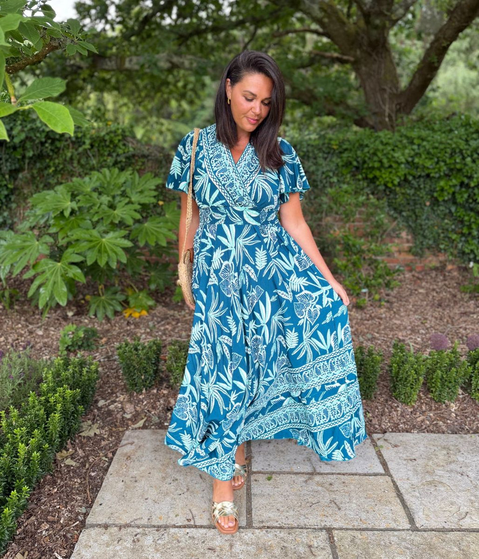 Woman wearing a blue floral dress standing in a garden