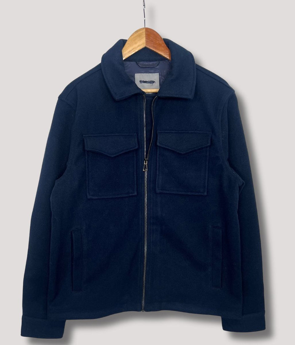 Navy blue jacket on a wooden hanger against a light gray background