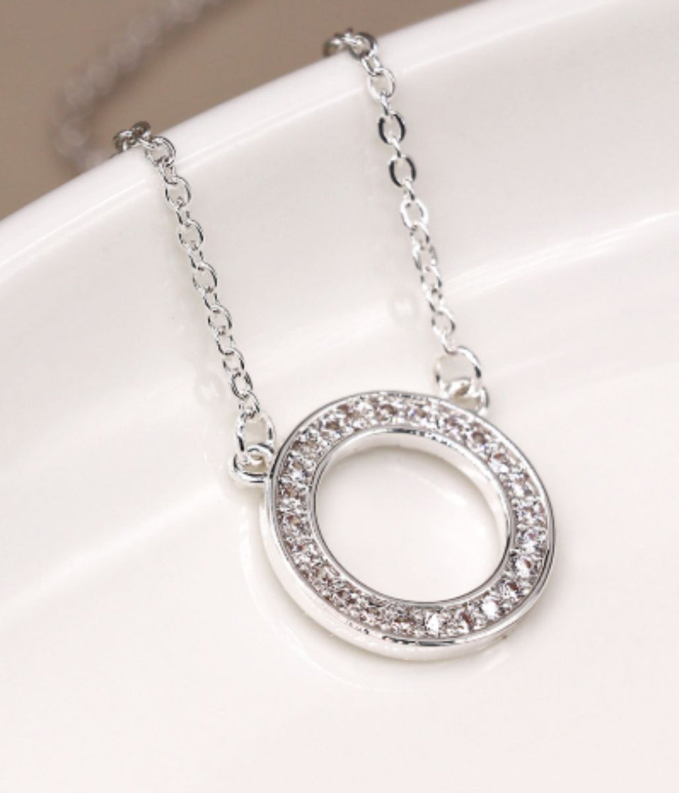 Silver necklace with a circular pendant on a white surface