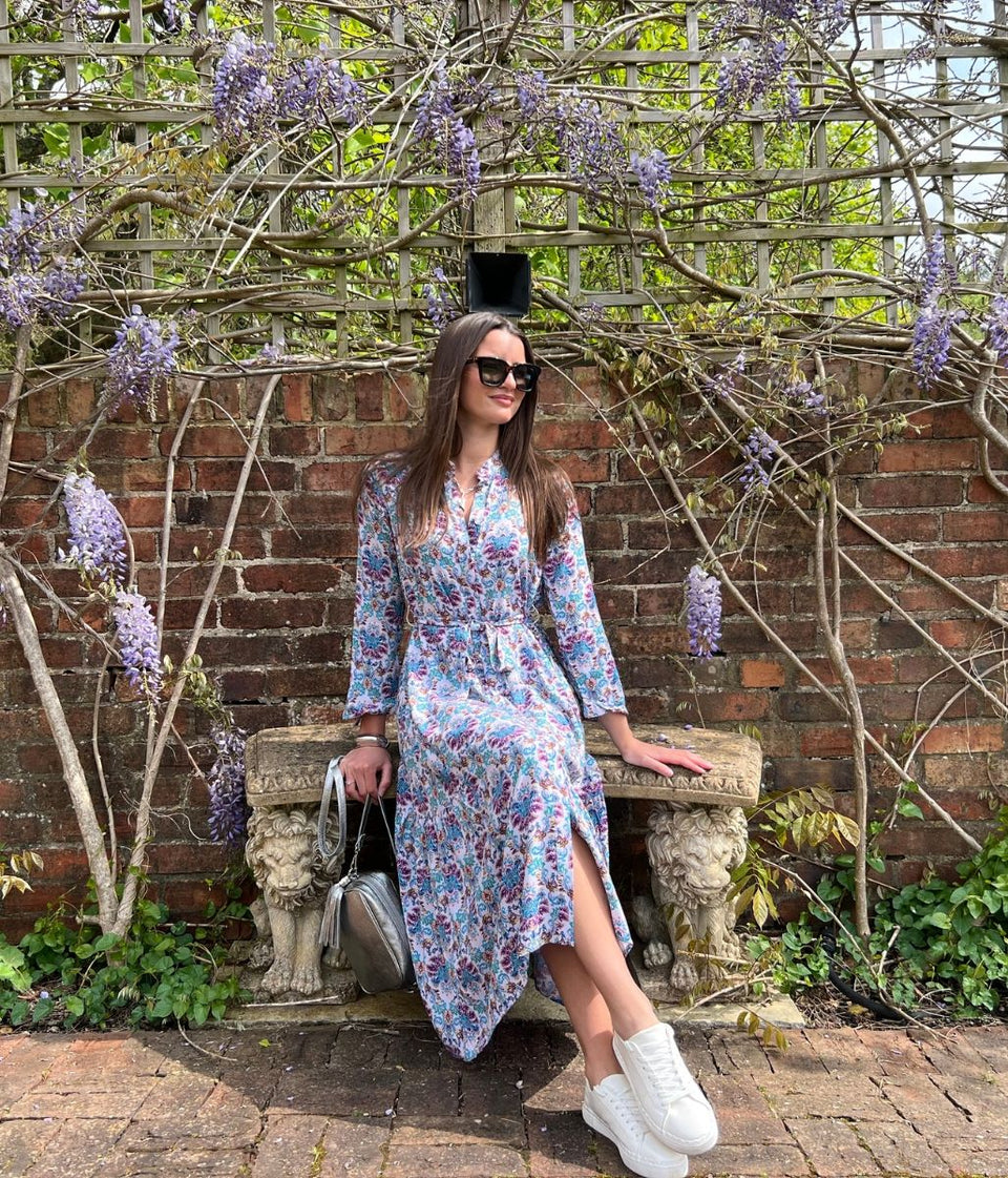 lilac boho summer dress, buttoned in a floral print front sitting on a bench