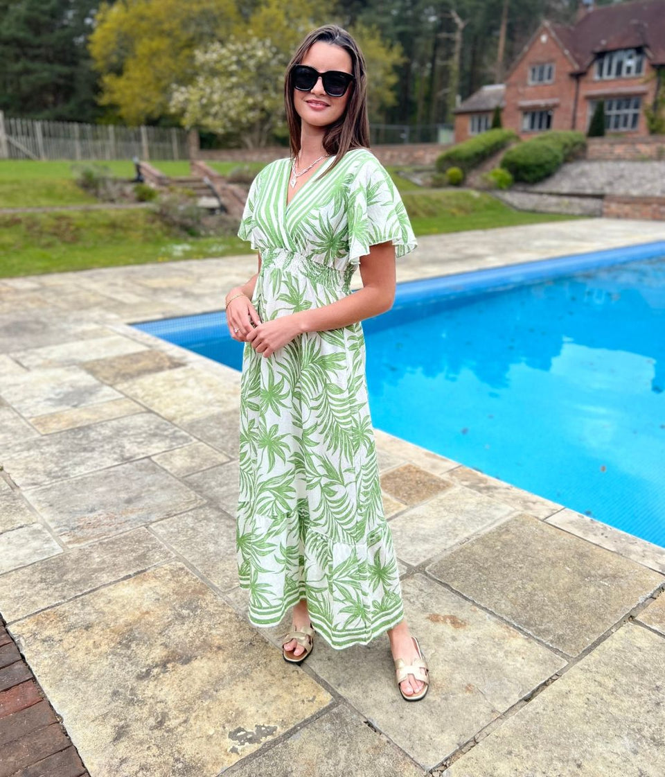 Sundress with a green boho floral print in front of a swimming pool