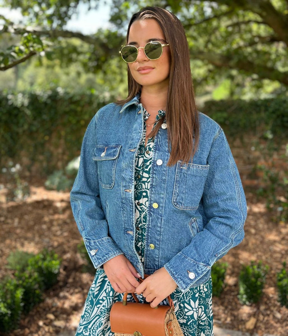 Woman wearing a denim jacket and floral dress outdoors