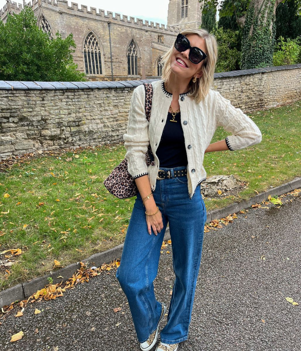 Woman in a stylish outfit standing on a street with a church in the background
