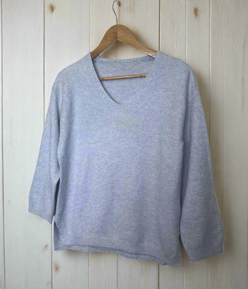 Light blue sweater on a wooden hanger against a white background